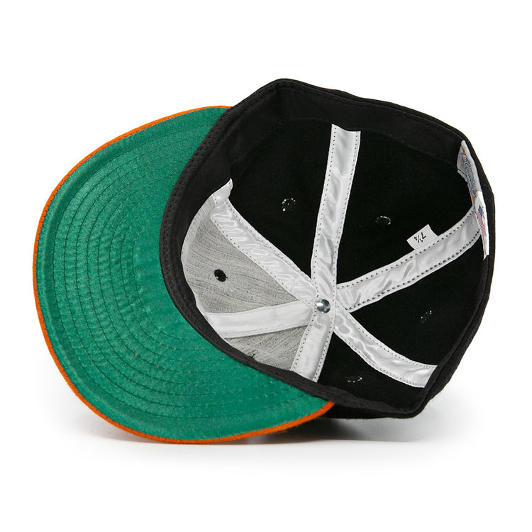 An overhead view of the Marianao Tigres 1950 Vintage Ballcap by Ebbets Field Flannels, flipped to reveal its green underbill, orange brim edge, and white interior lining—echoing classic Cuban Professional League style.