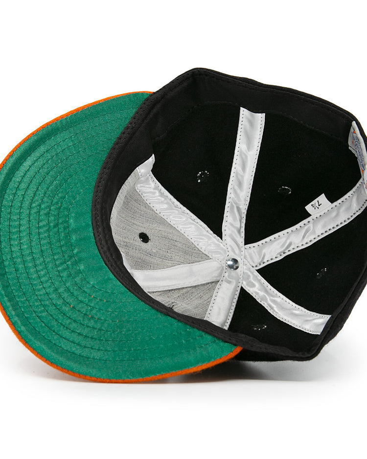 An overhead view of the Marianao Tigres 1950 Vintage Ballcap by Ebbets Field Flannels, flipped to reveal its green underbill, orange brim edge, and white interior lining—echoing classic Cuban Professional League style.