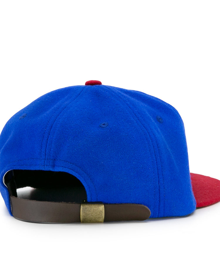 The EFF Montreal Royals 1935 Vintage Ballcap features a blue crown, red brim, and a brown adjustable strap with brass buckle, viewed from the back—a classic homage to baseball history.