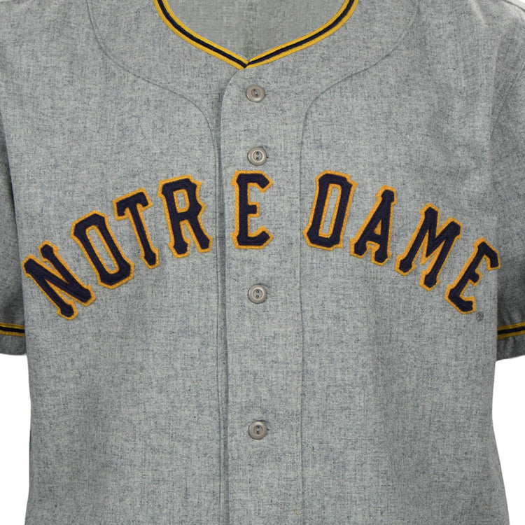 The EFF University of Notre Dame 1956 Road Jersey features gray flannel with yellow and navy trim, plus bold yellow NOTRE DAME lettering outlined in navy for a classic Collegiate Team Authentic style.