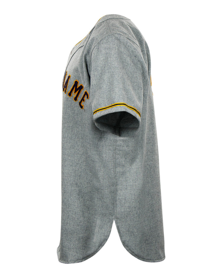 A side view of the EFF University of Notre Dame 1956 Road Jersey shows classic gray fabric with yellow sleeve trim and brown partial chest text, capturing the authentic Collegiate Team style.