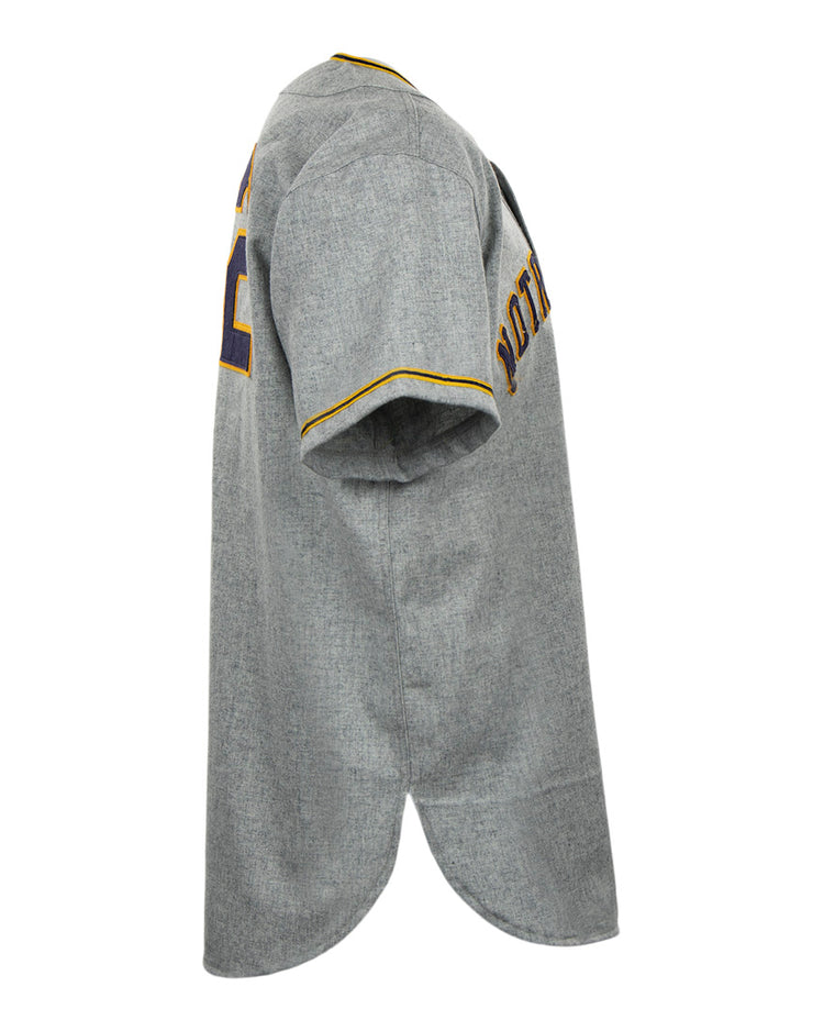 Side view of the EFF University of Notre Dame 1956 Road Jersey in gray, featuring yellow and purple trim on sleeves and collar. POTATO and number 22 appear on the back, emphasizing its Collegiate Team Authentic style.