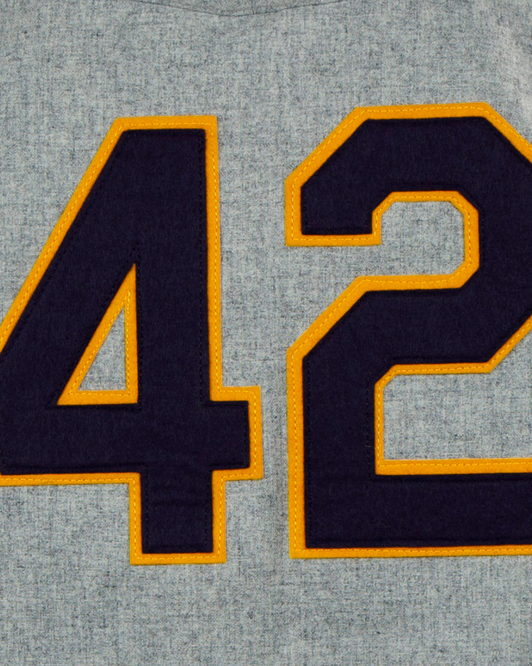 A large dark blue number 42 outlined in yellow is sewn onto gray fabric, echoing the classic style of the EFF University of Notre Dame 1956 Road Jersey.