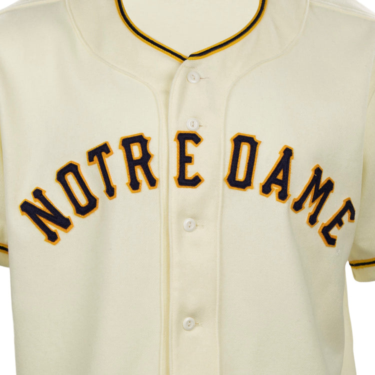 The EFF University of Notre Dame 1956 Home Jersey is an authentic cream flannel with NOTRE DAME in bold navy and gold lettering, white buttons, and black-and-gold collar trim, reflecting the classic 1956 baseball style.
