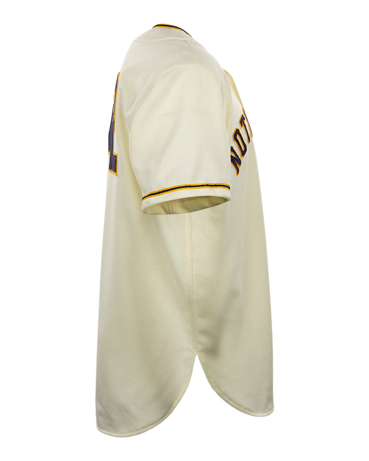 Side view of an authentic cream-colored University of Notre Dame 1956 Home Jersey by EFF, featuring yellow and black trim on the sleeve and collar, with partially visible text and numbers on the back and sleeve.