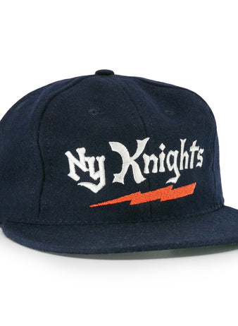 The EFF New York Knights City Series Ballcap features navy blue fabric with Ny Knights in white gothic embroidery and an orange lightning bolt, inspired by the hat from The Natural.