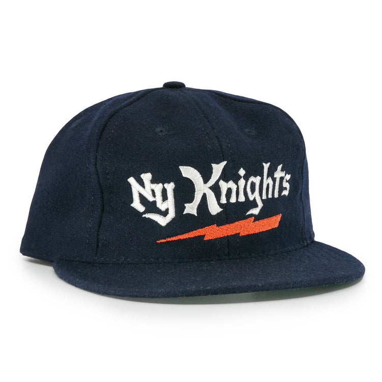 The EFF New York Knights City Series Ballcap features navy blue fabric with Ny Knights in white gothic embroidery and an orange lightning bolt, inspired by the hat from The Natural.