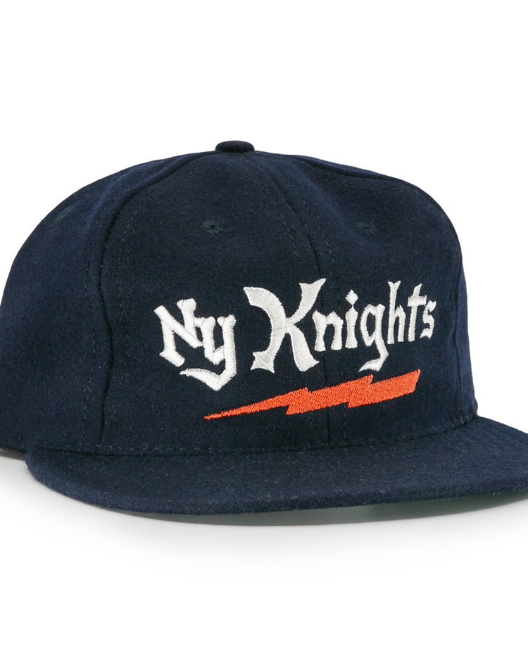 The EFF New York Knights City Series Ballcap features navy blue fabric with Ny Knights in white gothic embroidery and an orange lightning bolt, inspired by the hat from The Natural.