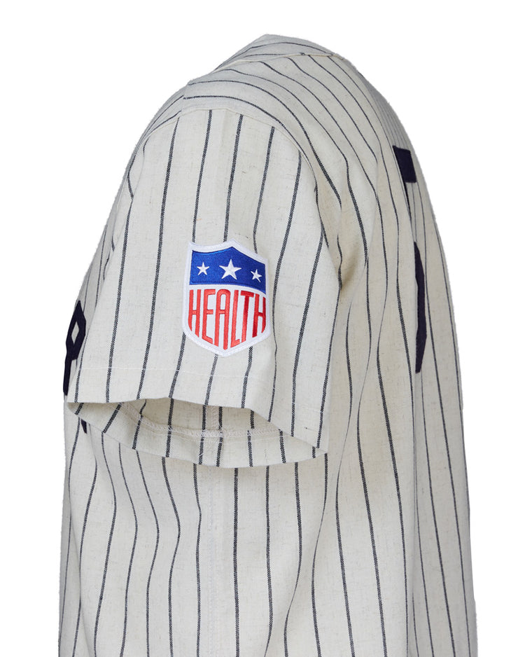Side view of a white pinstriped EFF New York Black Yankees 1942 Home Jersey sleeve with a red, white, and blue HEALTH patch and stars. The number 9 is partially visible on the back.