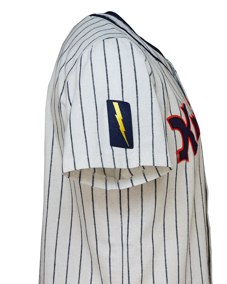 A close-up of the EFF New York Knights 1939 Home Jersey, a white pinstriped short-sleeve baseball jersey with a red chest logo and yellow lightning bolt patch on the left sleeve, inspired by The Natural.