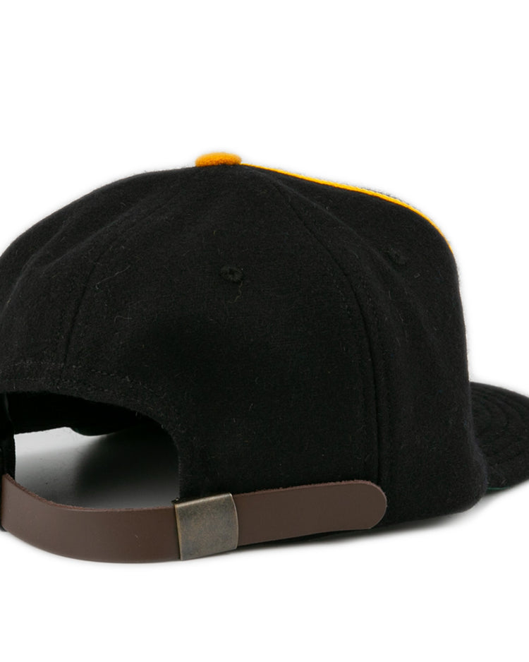 The Oakland Caskets Co. 1938 Vintage Ballcap by EFF is shown from the back, displaying a brown adjustable strap with metallic clasp. The curved brim and yellow crown accent are partially visible. Made in USA for lasting quality.