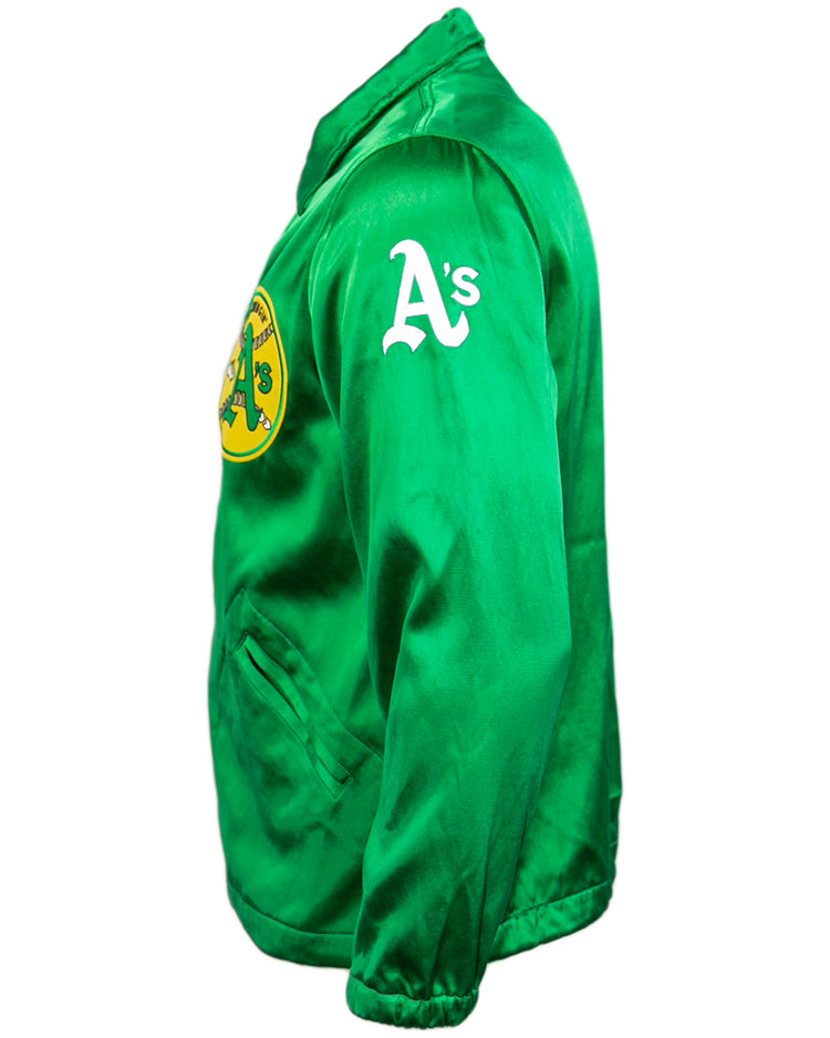 The EFF Oakland As 1971 Satin Windbreaker features a green satin finish, front elephant logo, As lettering on the left sleeve, and vintage MLB style—shown here from a side angle.