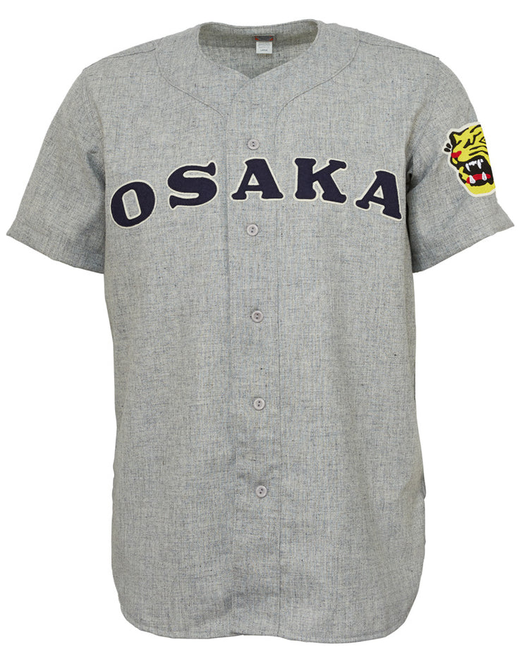 The EFF Osaka Tigers 1959 Road Jersey is a gray Japanese baseball jersey with OSAKA in bold black letters across the chest, a yellow tiger head patch on the left sleeve, button front, and short sleeves—classic Tigers inspiration.