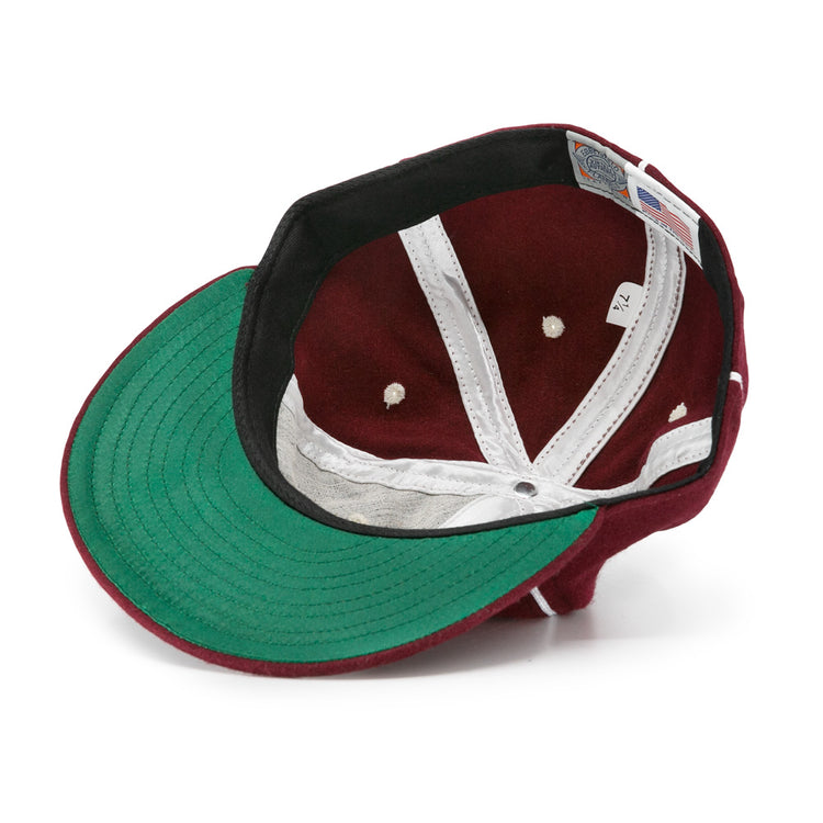 An EFF Quebec Athletics 1941 Vintage Ballcap in maroon, shown inside out to reveal its green underside brim, white lining, black sweatband, and size tag (7 1/2), crafted from genuine wool baseball cloth for an authentic vintage look.