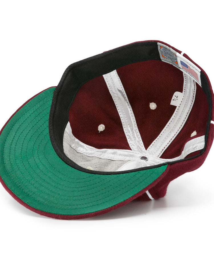 An EFF Quebec Athletics 1941 Vintage Ballcap in maroon, shown inside out to reveal its green underside brim, white lining, black sweatband, and size tag (7 1/2), crafted from genuine wool baseball cloth for an authentic vintage look.