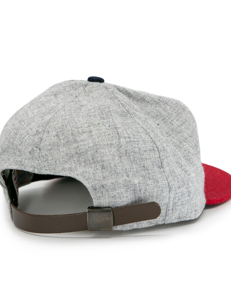 The Ebbets Field Flannels Regina Nationals 1933 Vintage Ballcap has a light gray crown, red brim, and adjustable dark brown strap with metal clasp. Inspired by classic ballcaps, its shown from the back against a white background.