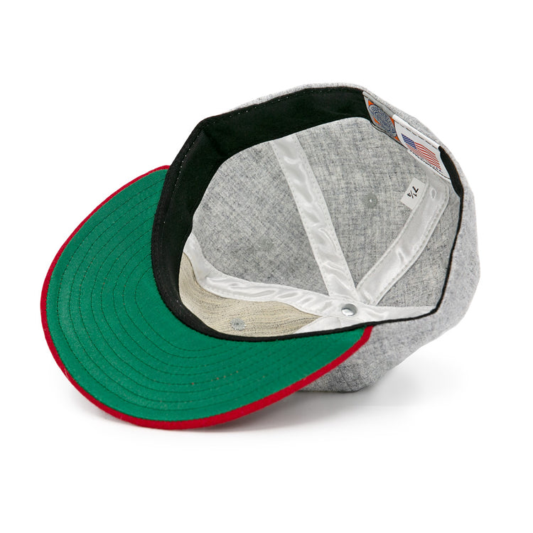 The Regina Nationals 1933 Vintage Ballcap by Ebbets Field Flannels is shown inside out, highlighting its green brim underside with a red edge, white inner lining, and visible tag.