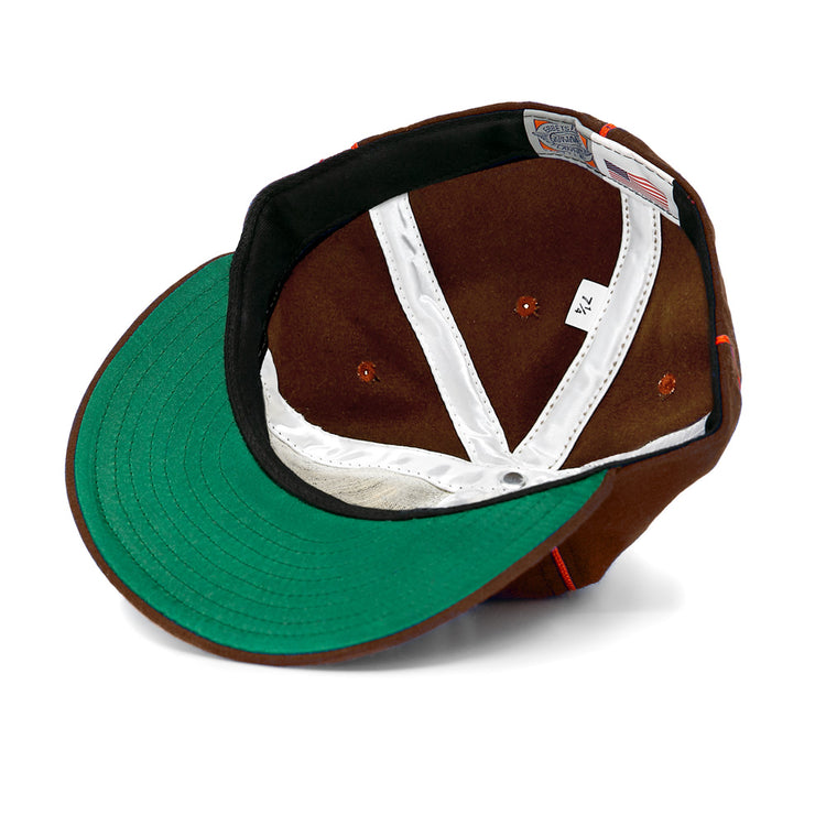 An EFF San Antonio Missions 1939 Vintage Ballcap in brown, turned inside out to show its green under-brim, white stitching, gray tag, “7 1/4” size label, and an American flag tag near the edge.