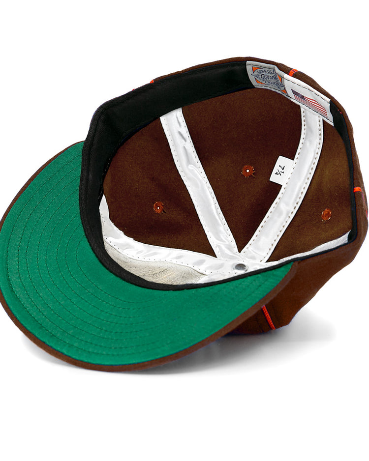 An EFF San Antonio Missions 1939 Vintage Ballcap in brown, turned inside out to show its green under-brim, white stitching, gray tag, “7 1/4” size label, and an American flag tag near the edge.