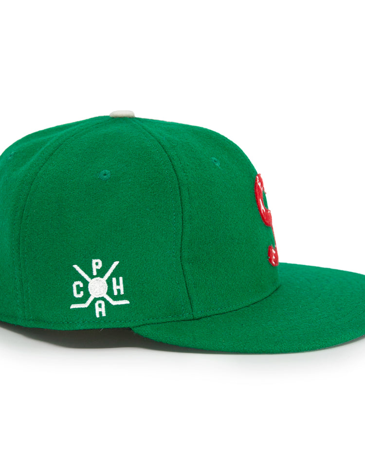 The EFF Seattle Metropolitans 1917 Vintage Ballcap is a green cap with a flat brim and a white embroidered side logo featuring C P H around a bat and ball, inspired by classic hockey hats. The front of the cap is partially visible.