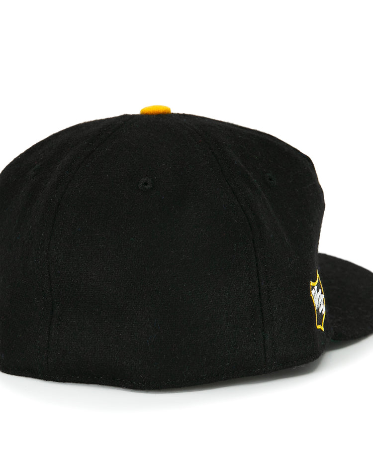 The EFF San Francisco Seals 1963 Vintage Ballcap is a black wool cap seen from the back, with a yellow top button and a yellow and white embroidered Seals logo near the closure.