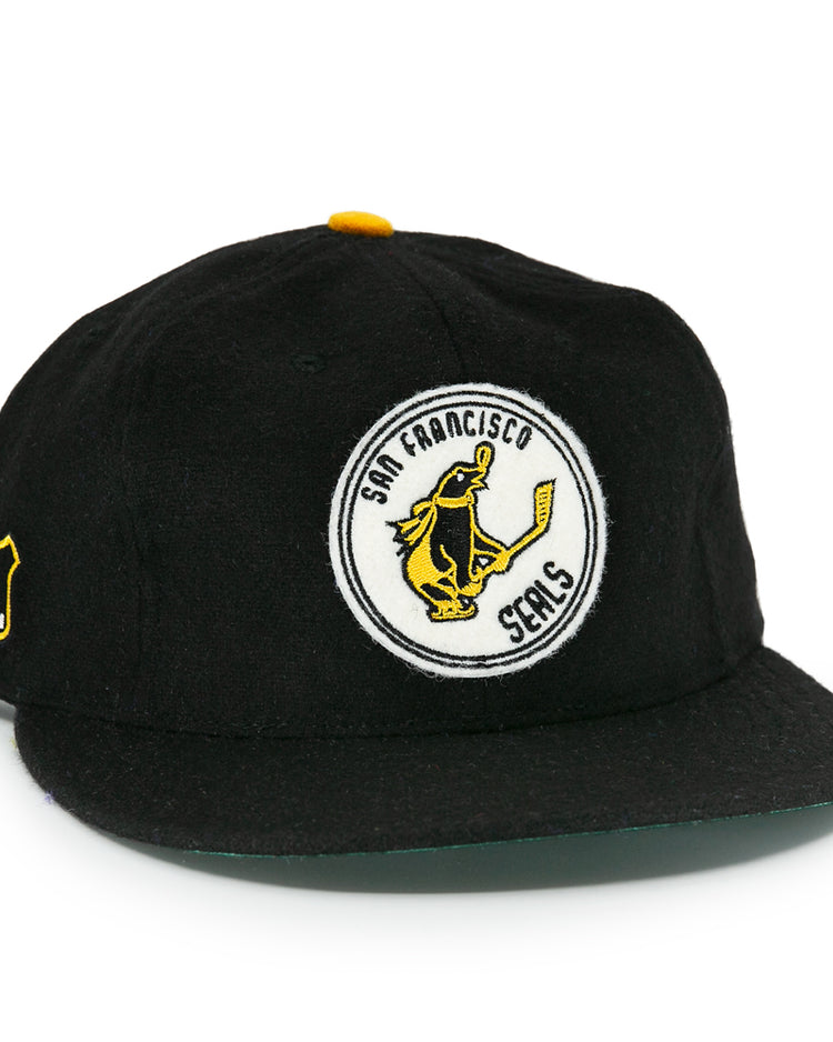 The EFF San Francisco Seals 1963 Vintage Ballcap features a hockey-playing seal logo on the front, an NHL shield patch, a flat brim, and yellow button—honoring the team’s Western Hockey League heritage.
