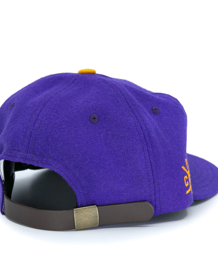 The EFF Spokane Canaries 1917 Vintage Ballcap is a purple wool cap with a brown adjustable leather strap, brass buckle, and a small yellow embroidered front design inspired by classic Pacific Coast Hockey Association style.