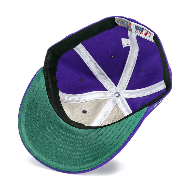 The image shows the inside of an EFF Spokane Canaries 1917 Vintage Ballcap, featuring a purple wool crown, green underside brim, white stitching, and inner labels including an American flag tag.