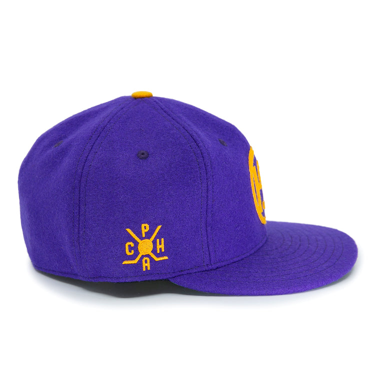 The EFF Spokane Canaries 1917 Vintage Ballcap is a purple wool cap with a yellow embroidered C P H A crossed bats logo, inspired by the Pacific Coast Hockey Association. It features an adjustable leather strap and a yellow top button.