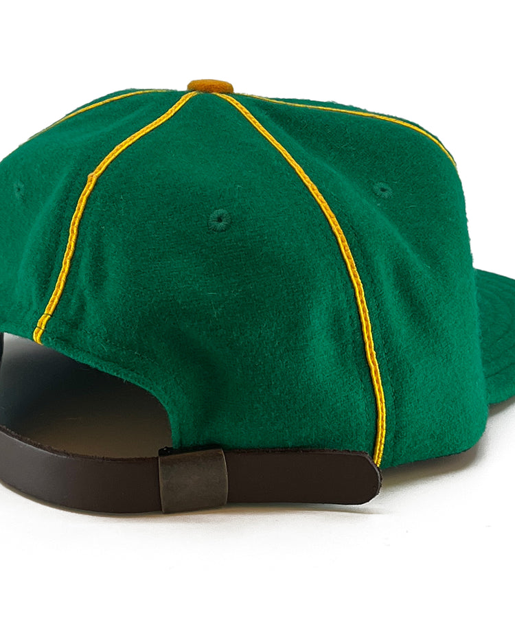 The EFF St. Patrick Shamrocks 1925 Vintage Ballcap is a green wool baseball cap with yellow piping, shown from the back. It features a brown adjustable strap with a metal buckle, inspired by the classic ballcap design.