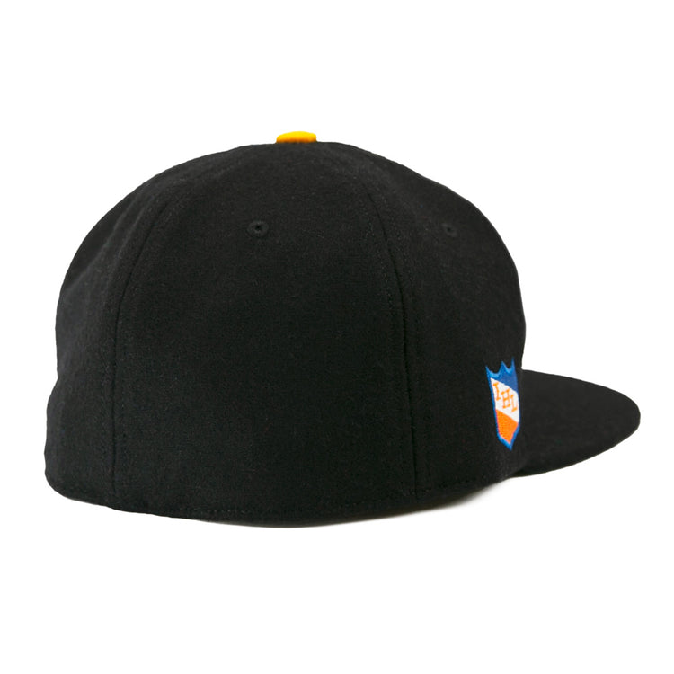 The EFF St. Paul Fighting Saints 1961 Vintage Ballcap is a black wool cap with a yellow top button, blue and orange shield logo on the right side, and classic styling inspired by the Saints hockey team.