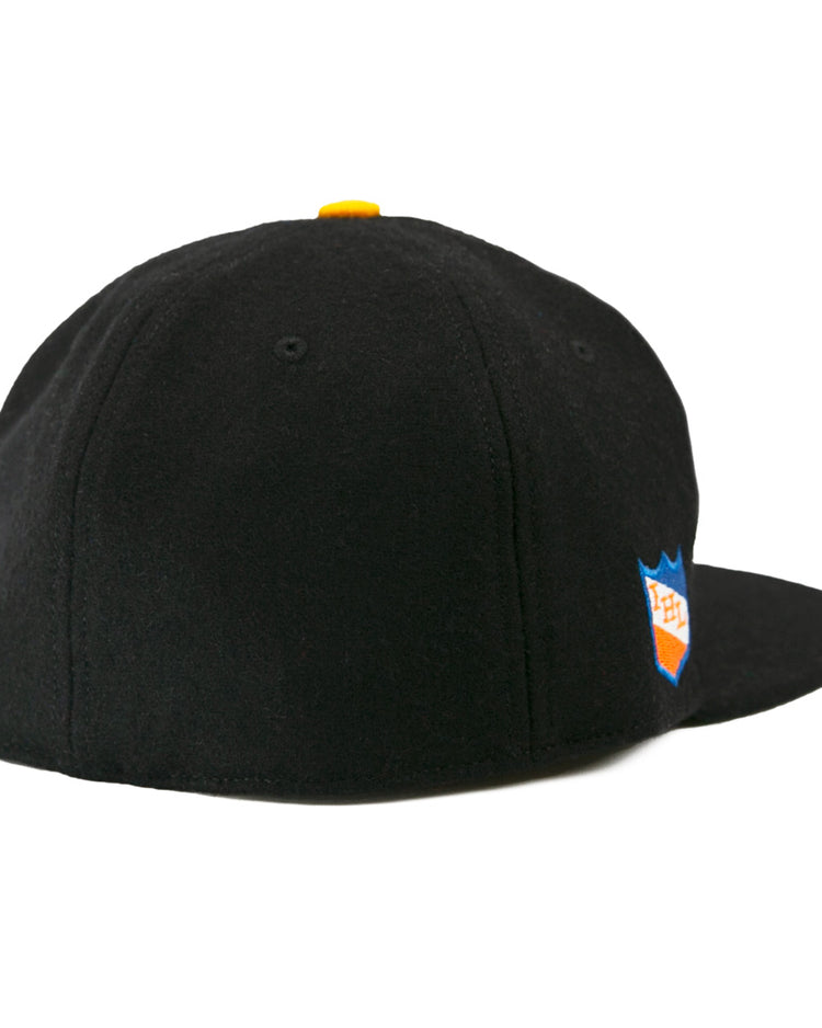 The EFF St. Paul Fighting Saints 1961 Vintage Ballcap is a black wool cap with a yellow top button, blue and orange shield logo on the right side, and classic styling inspired by the Saints hockey team.