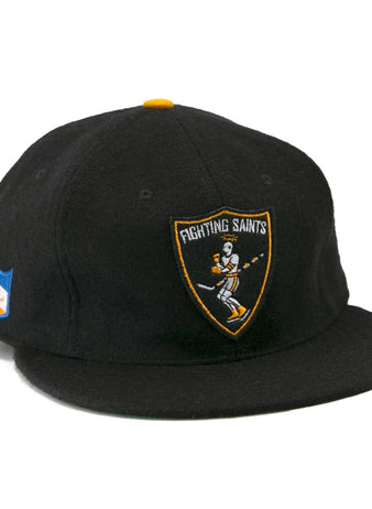 The EFF St. Paul Fighting Saints 1961 Vintage Ballcap is a black cap featuring a skeleton-hockey-stick Fighting Saints logo on the front and a blue/orange shield patch on the side—ideal for any Saints hockey fan.