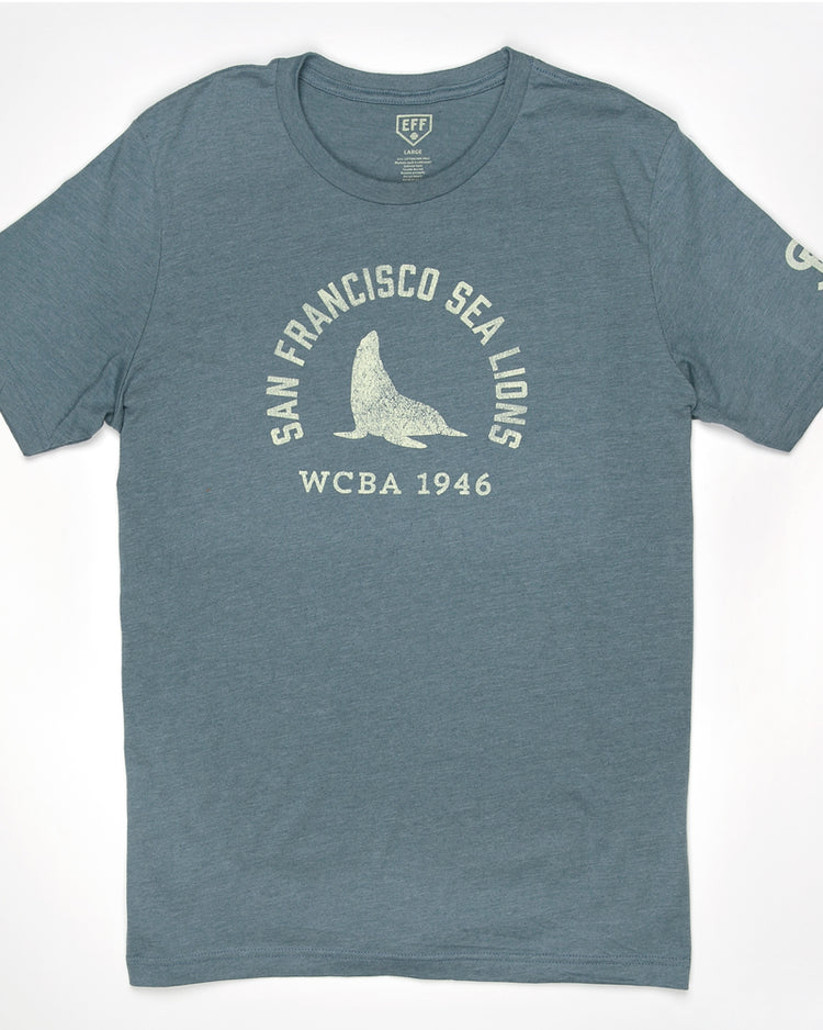 The EFF San Francisco Sea Lions 1946 T-Shirt is a unisex premium cotton heathered tee in blue, featuring white San Francisco Sea Lions WCBA 1946 text and a central sea lion graphic, inspired by the West Coast Baseball Association.