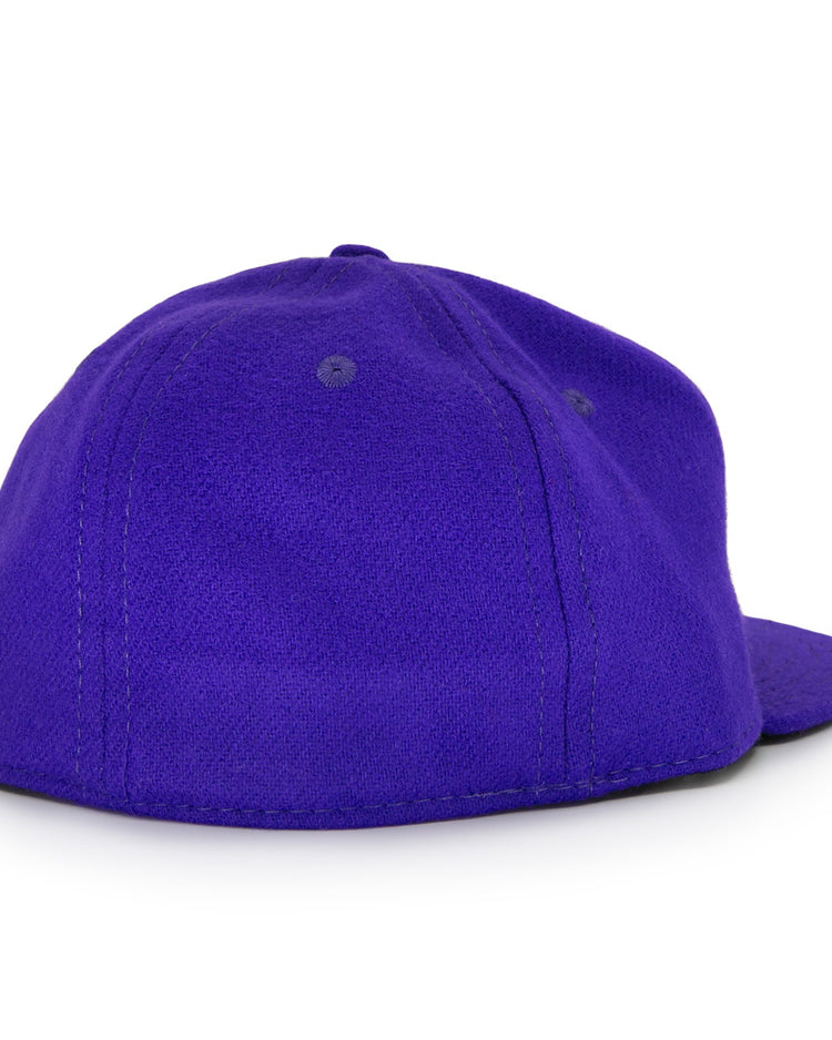 The Ebbets Field Flannels Club Teléfonos 1943 Vintage Ballcap is shown from the back, revealing its plain purple wool design with a flat brim and two stitched eyelets on top, without any visible logos or designs.