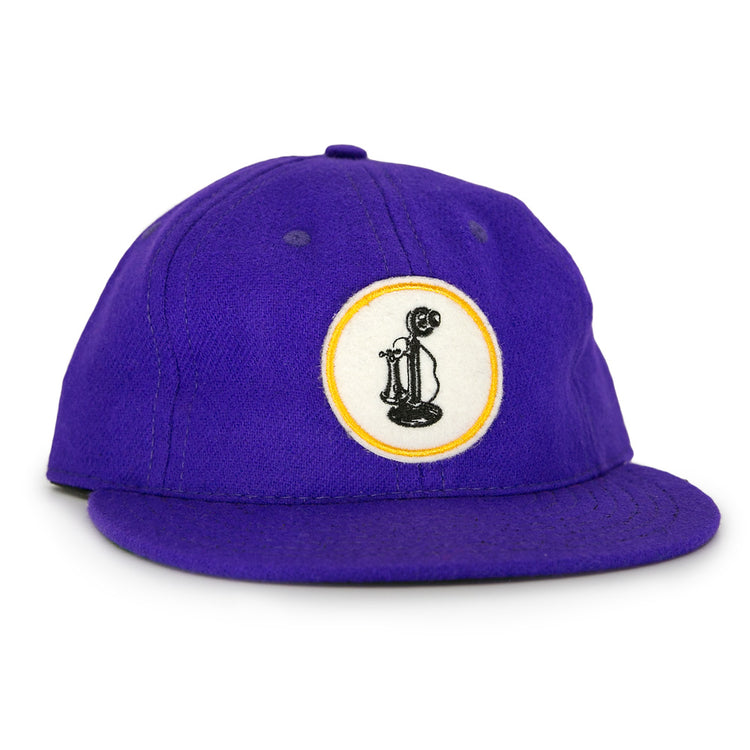 The Ebbets Field Flannels Club Teléfonos 1943 Vintage Ballcap is purple and features a front circular patch with a yellow-outlined black rotary phone design.