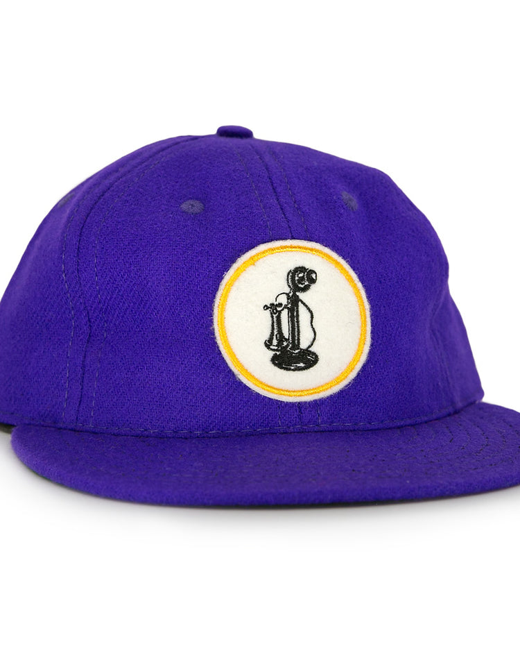 The Ebbets Field Flannels Club Teléfonos 1943 Vintage Ballcap is purple and features a front circular patch with a yellow-outlined black rotary phone design.
