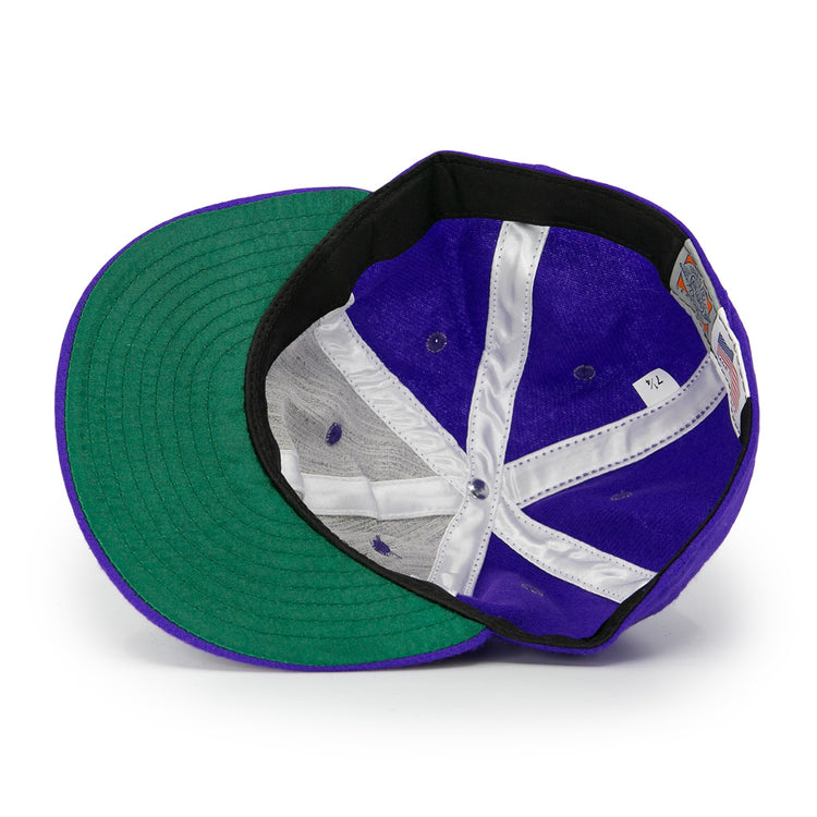 Interior view of the Club Teléfonos 1943 Vintage Ballcap by Ebbets Field Flannels, featuring a purple crown, green underbill, white stitching, black sweatband, and attached size tag.