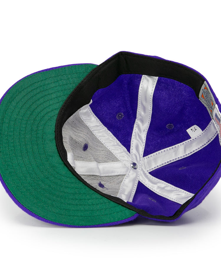 Interior view of the Club Teléfonos 1943 Vintage Ballcap by Ebbets Field Flannels, featuring a purple crown, green underbill, white stitching, black sweatband, and attached size tag.