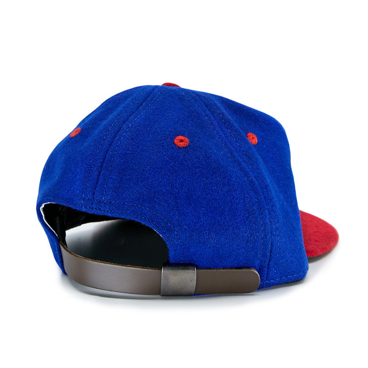 The EFF Utica Blue Sox 1950 Vintage Ballcap is a blue cap with red accents, seen from the back, featuring a brown adjustable strap and a partially visible red brim—capturing classic team style.