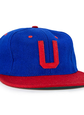 The EFF Utica Blue Sox 1950 Vintage Ballcap is blue with a red brim, red stitching, and a bold red U on the front—replicating the classic look of an original Utica Blue Sox cap.