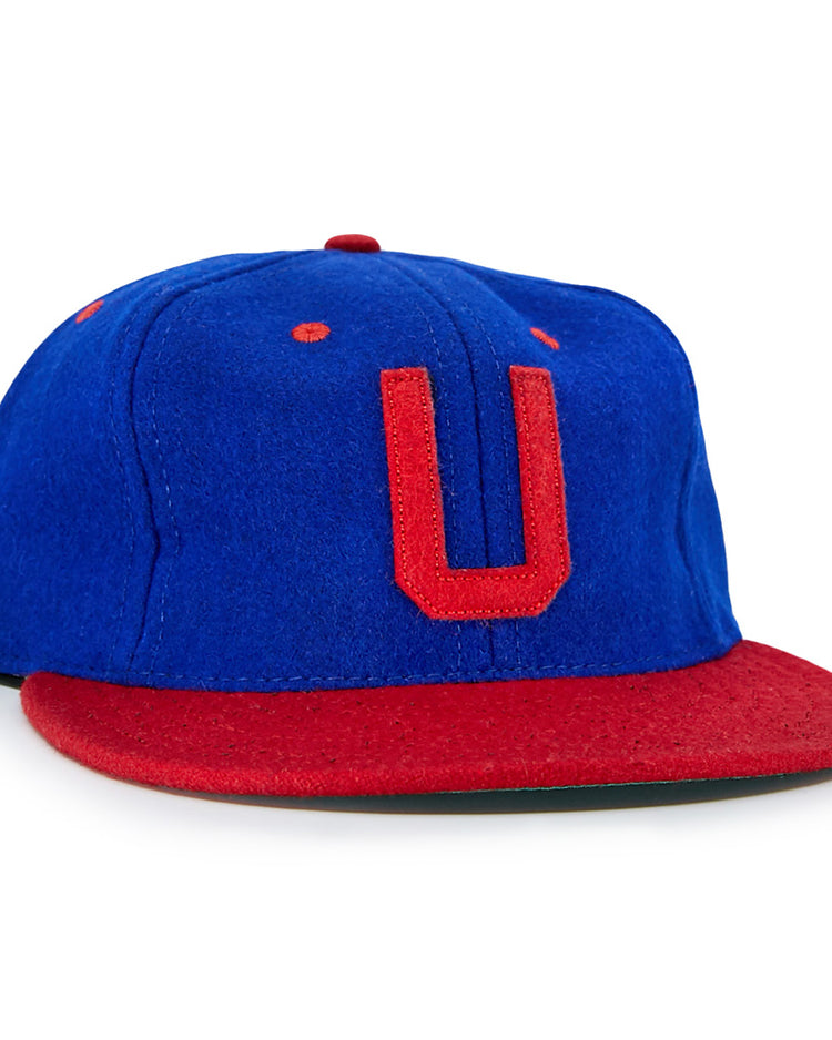 The EFF Utica Blue Sox 1950 Vintage Ballcap is blue with a red brim, red stitching, and a bold red U on the front—replicating the classic look of an original Utica Blue Sox cap.