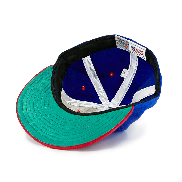 The EFF Utica Blue Sox 1950 Vintage Ballcap is shown inside out, featuring a green brim with a red edge, blue interior with white and red accents, and an American flag tag with size info. This classic wool baseball hat is an eye-catching throwback.