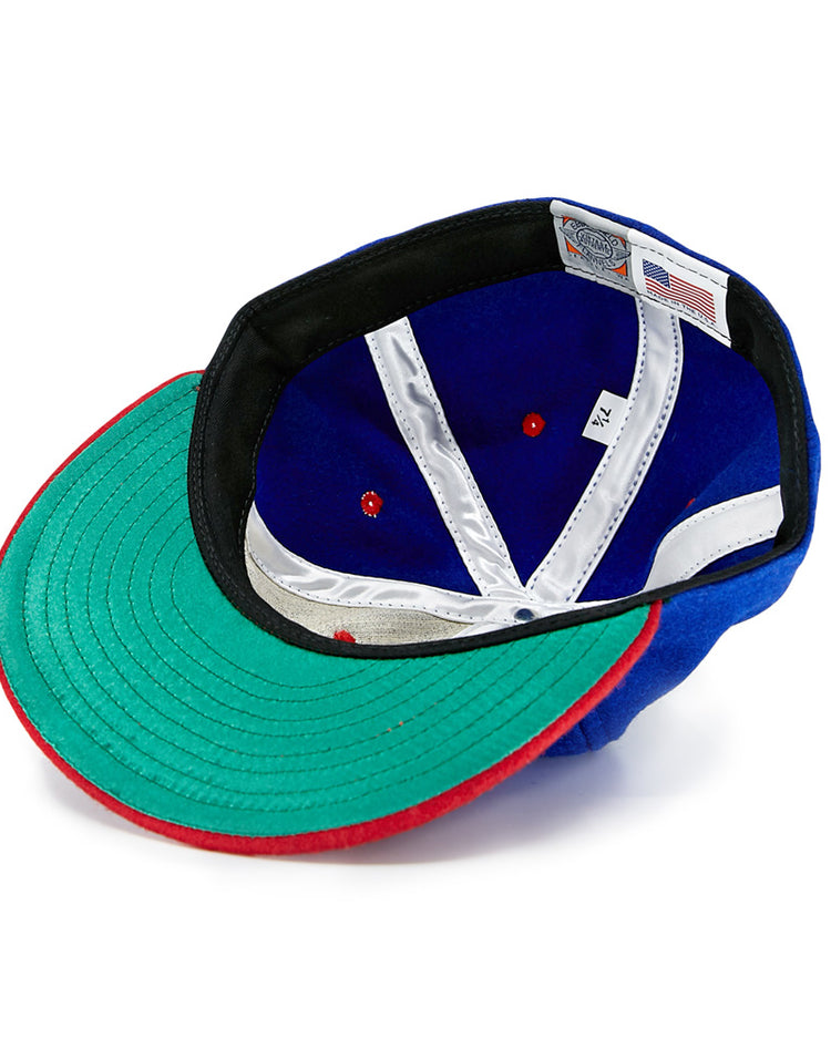 The EFF Utica Blue Sox 1950 Vintage Ballcap is shown inside out, featuring a green brim with a red edge, blue interior with white and red accents, and an American flag tag with size info. This classic wool baseball hat is an eye-catching throwback.