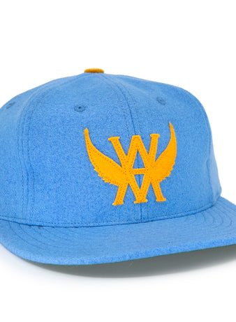 The EFF Victoria Aristocrats 1915 Vintage Ballcap is a blue wool cap with a yellow winged WA emblem on the front and a small yellow side graphic, inspired by the Pacific Coast Hockey Association’s Victoria Cougars.