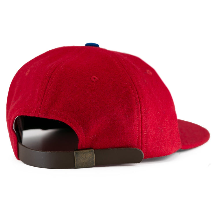The Wembley Lions 1957 Vintage Ballcap by EFF is a red wool hat with a brown adjustable strap, brass buckle, and slightly curved brim, capturing the classic British National Hockey League style.