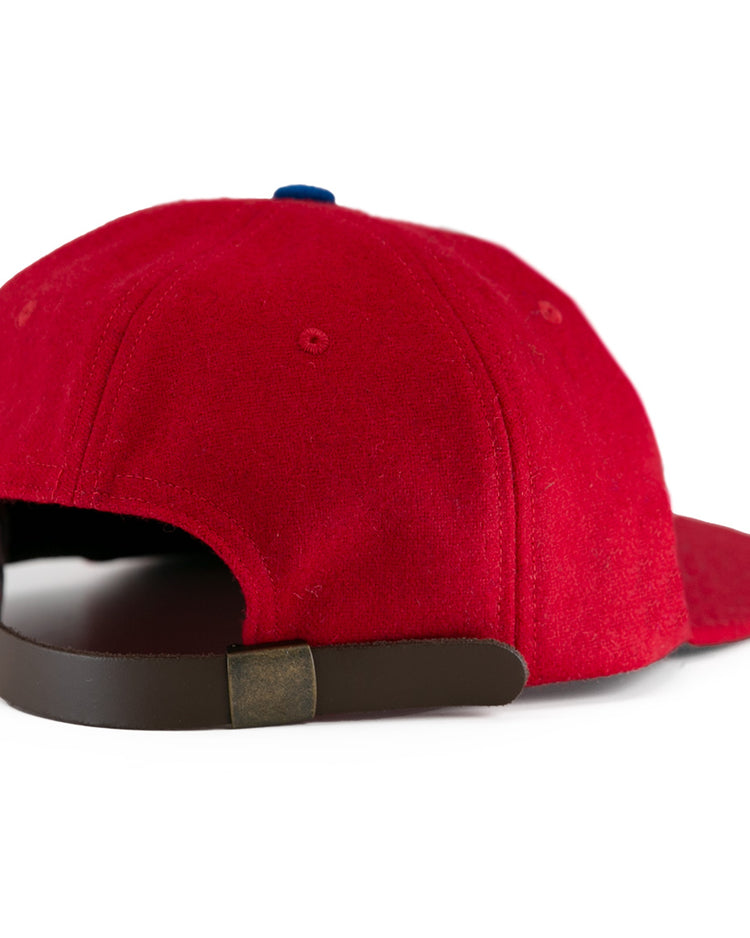 The Wembley Lions 1957 Vintage Ballcap by EFF is a red wool hat with a brown adjustable strap, brass buckle, and slightly curved brim, capturing the classic British National Hockey League style.
