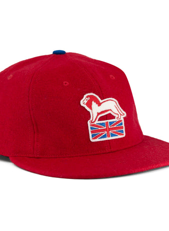 The EFF Wembley Lions 1957 Vintage Ballcap is a red wool cap with an embroidered white lion on a Union Jack, blue top button, and flat brim—reflecting classic British National Hockey League style.