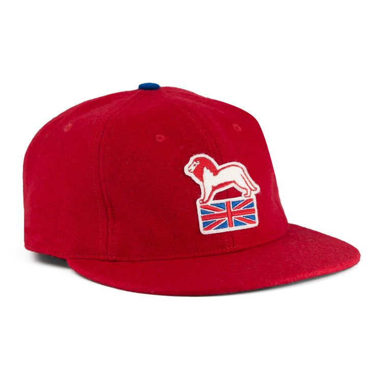 The EFF Wembley Lions 1957 Vintage Ballcap is a red wool cap with an embroidered white lion on a Union Jack, blue top button, and flat brim—reflecting classic British National Hockey League style.