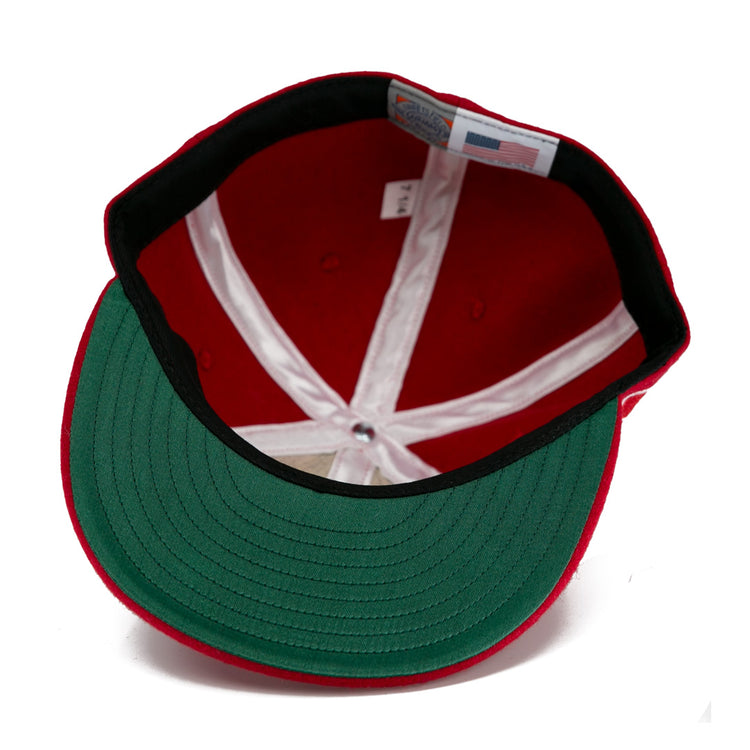 The EFF Wembley Lions 1957 Vintage Ballcap in red features a green underbrim, white stitched panels, and an inside label—a classic hand-sewn wool style inspired by British National Hockey League heritage.